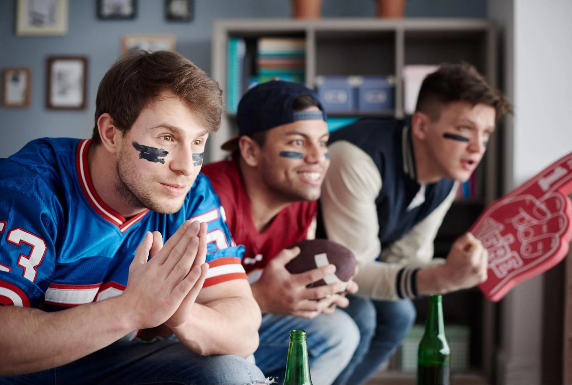 Close up of three fans wearing sports clothes watching Euroleague results